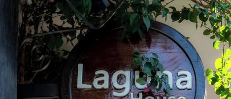 Un letrero de madera con el texto 'Laguna House' colgado sobre una puerta.
