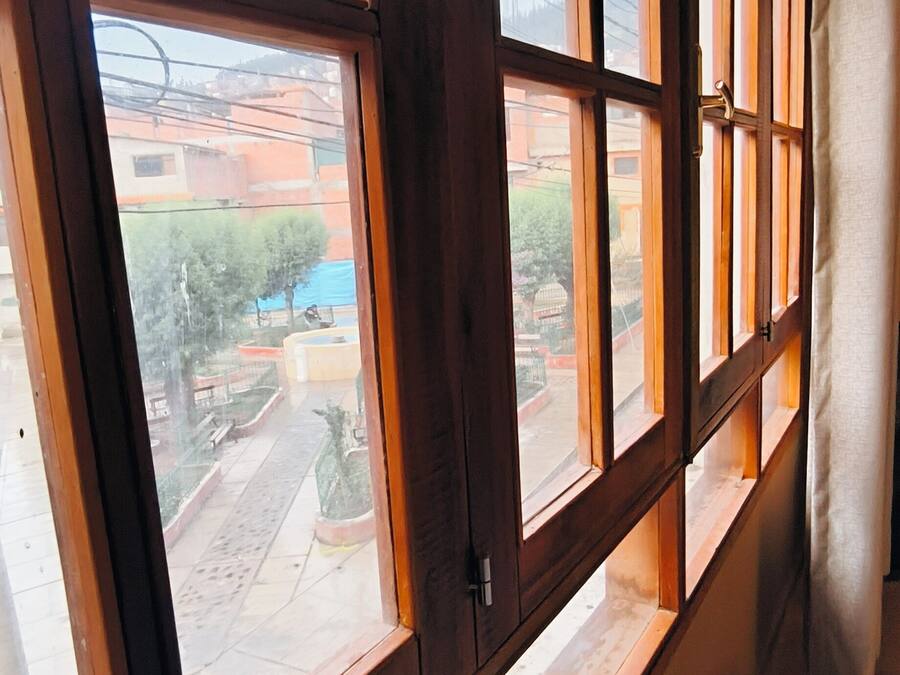 A room with large windows, a bed, and a curtain.