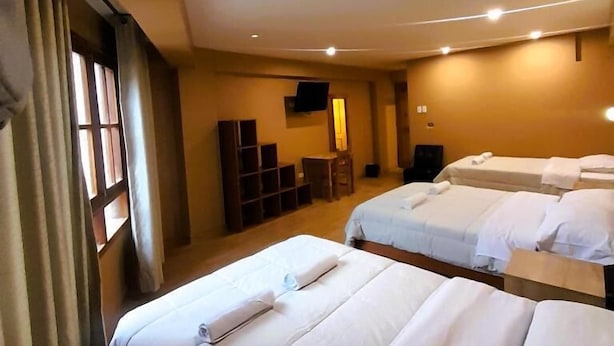 Hotellihuone, jossa on kaksi sänkyä, työpöytä, tuoli, televisio ja ikkuna, jossa on verhot.