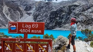 Señal de sendero de montaña con vista a un lago, un excursionista y una mochila.