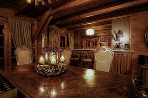 A wooden dining table with candles, chairs, and a vase with flowers.