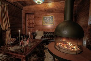 Une pièce chaleureuse avec une cheminée, un canapé, une table basse avec des bougies et des murs en bois.