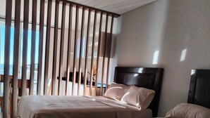 Habitación de hotel con dos camas, un ventanal grande y vistas al exterior.