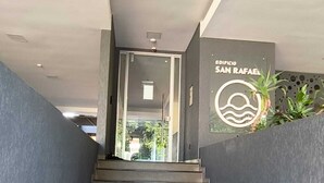Una escalera conduce a la entrada de un edificio, donde se lee la señalización 'EDIFICIO SAN RAFAEL'.