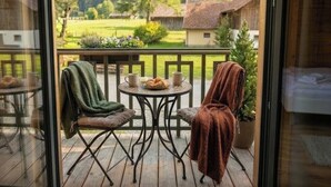 Un balcon avec une table et des chaises, un pot de fleurs et une vue sur un paysage rural.
