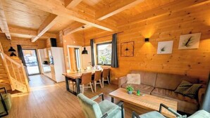 L’intérieur d’un chalet en bois comprend un coin repas, un canapé et un escalier menant à une autre pièce.
