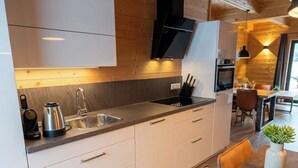 Une cuisine moderne avec des meubles blancs, un évier en acier inoxydable et une cuisinière intégrée.