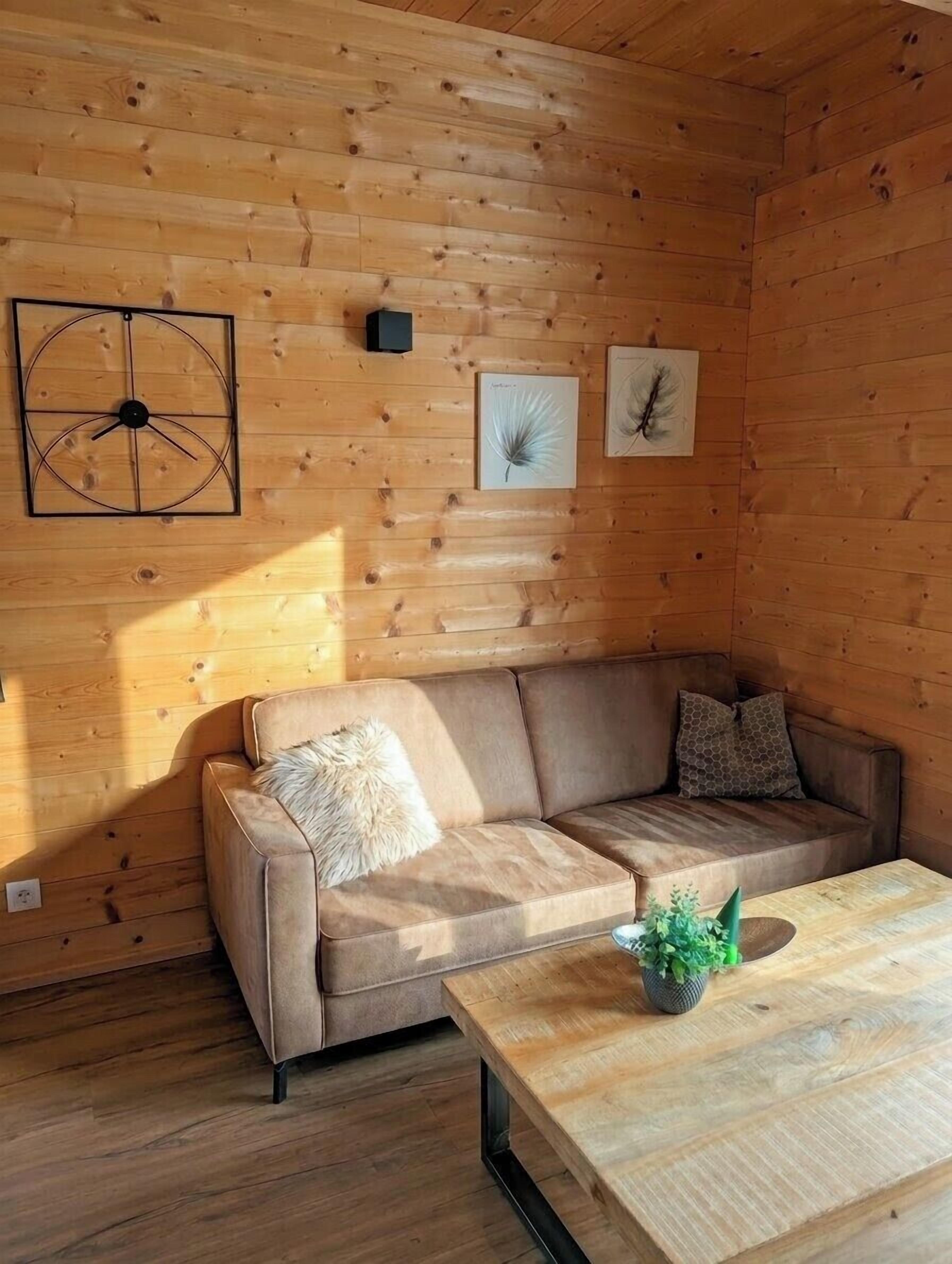 Une pièce aux murs lambrés, avec un canapé, une table basse et des œuvres d’art accrochées au mur.