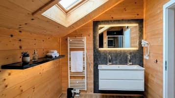 A wooden cabin bathroom with a skylight, a white sink, and a towel rack.
