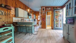 Maalaishenkinen keittiö, jossa on puuseinät, baaritiski ja jääkaappi.
