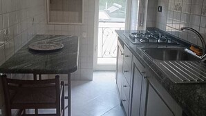 Uma cozinha compacta com mesa de jantar, armários e vista através de uma porta de vidro.
