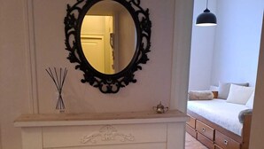 A room with a white vanity, a decorative mirror, a small vase, and a bed with a hanging light. - Appart l'Elégant in the historic center of Saumur (Saumur)