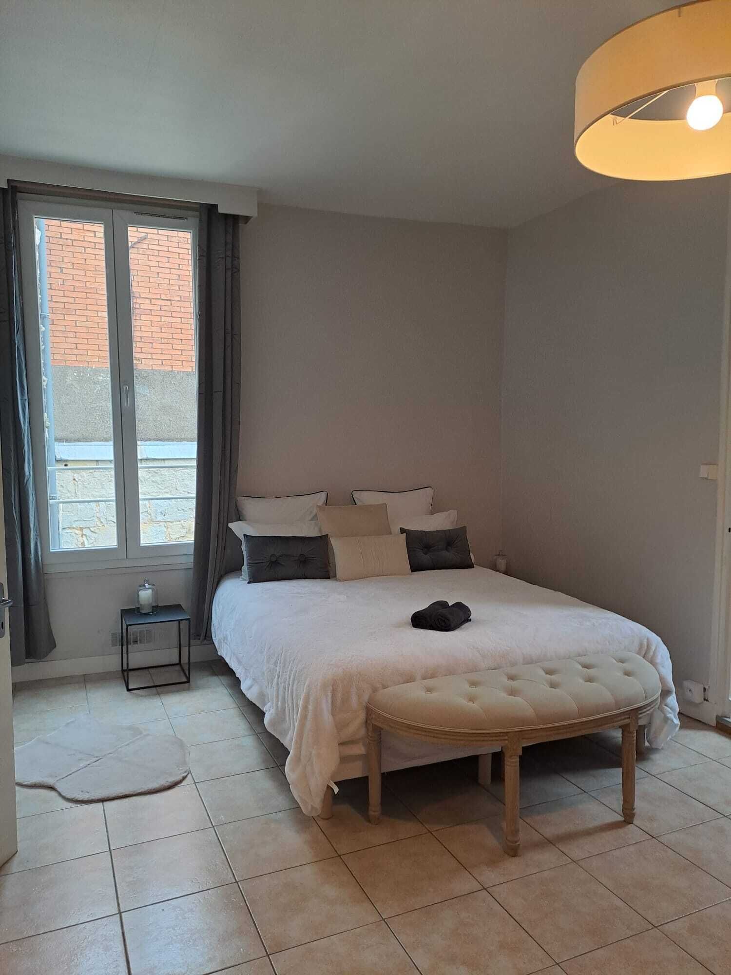 Une chambre à coucher avec un lit, une table de chevet, une lampe et une fenêtre.