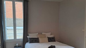 A bedroom with a bed, bedside table, lamp, and window. - Appart l'Elégant in the historic center of Saumur (Saumur)