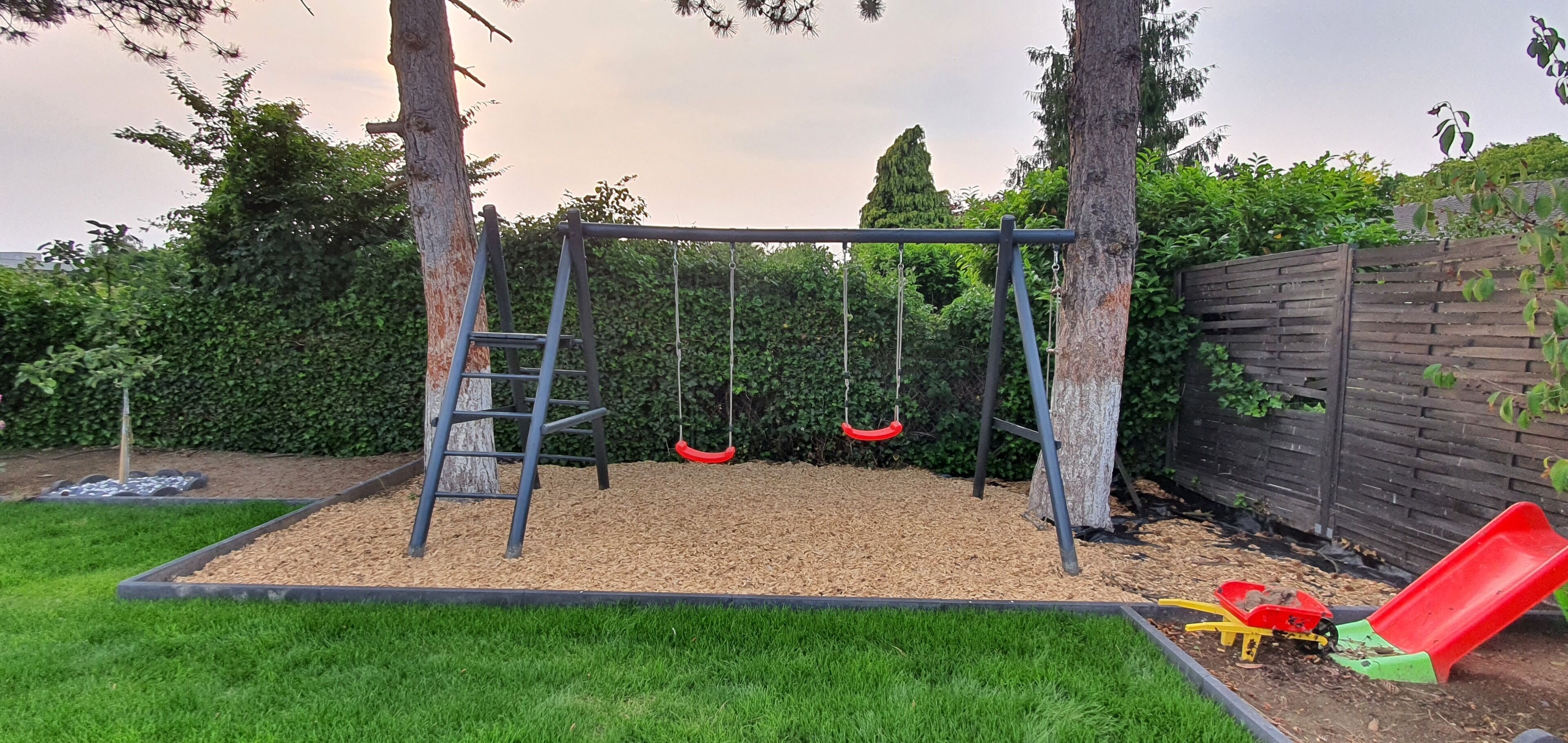 Ein Spielplatz mit Schaukel, Rutsche und Kletterstange.