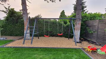 Ein Spielplatz mit Schaukel, Rutsche und Kletterstange.