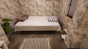 A small, cozy room with a bed, a patterned pillow, a plant, and a striped rug. - Quiet apartment with garden & terrace, parking space (Neuss)