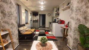 A compact living space with a sofa, a small kitchen area, and a dining table. - Quiet apartment with garden & terrace, parking space (Neuss)