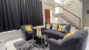 Uma sala de estar moderna com um conjunto de sofá, uma mesa de centro de vidro e uma escada.