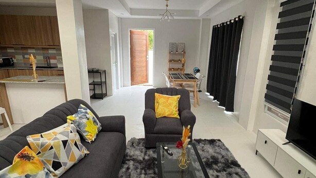 Uma sala de estar moderna com um sofá, poltronas, uma mesa de centro e uma TV.