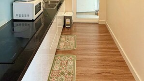 Una cocina compacta con microondas, pileta y un ventanal pequeño.