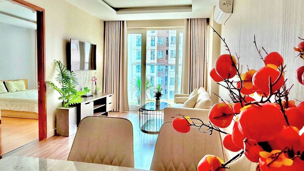 Una habitación de hotel moderna con cama, escritorio, zona de comedor y un ventanal con vista a la ciudad.