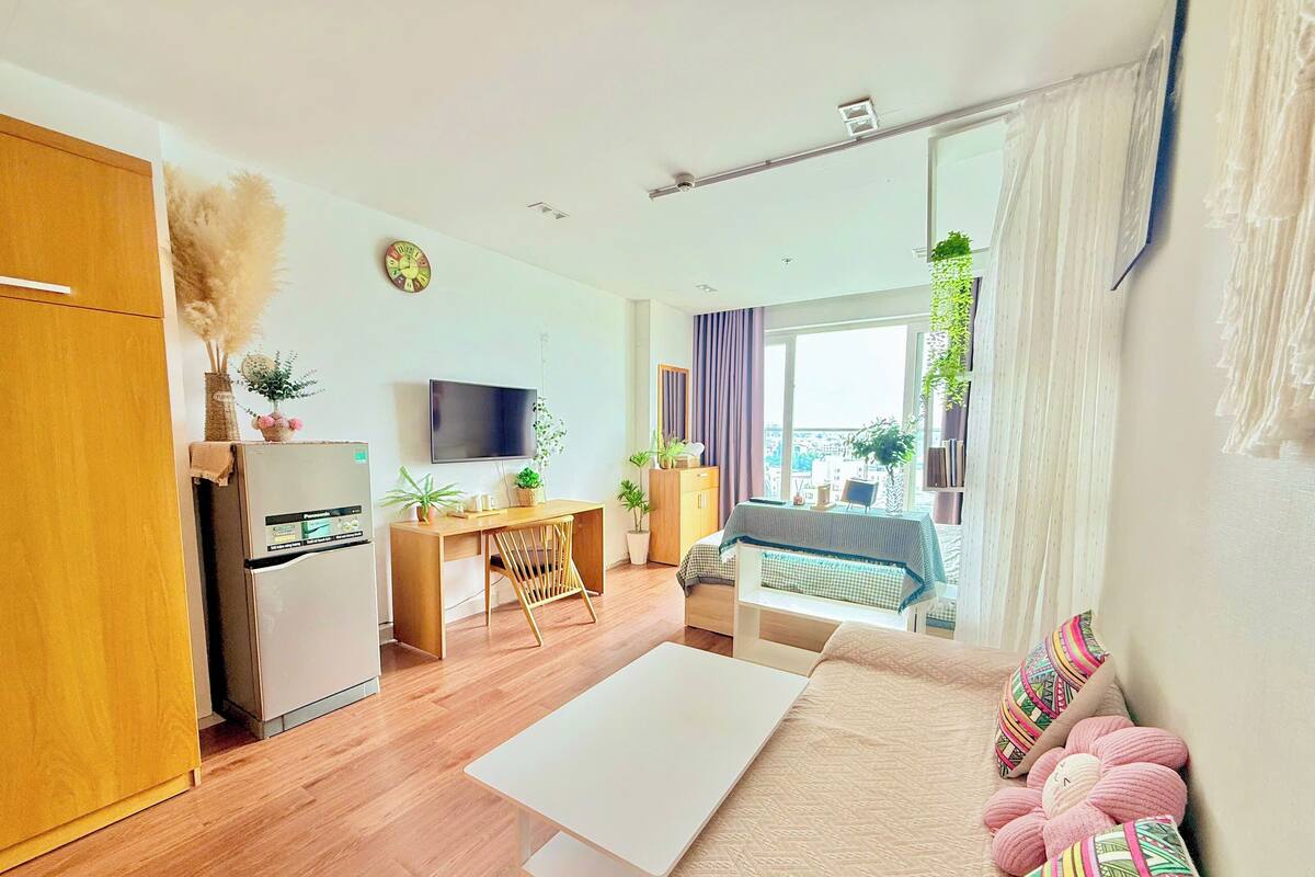 A modern apartment with a kitchen, dining area, and living room. It includes a sofa, a TV, and a dining table.