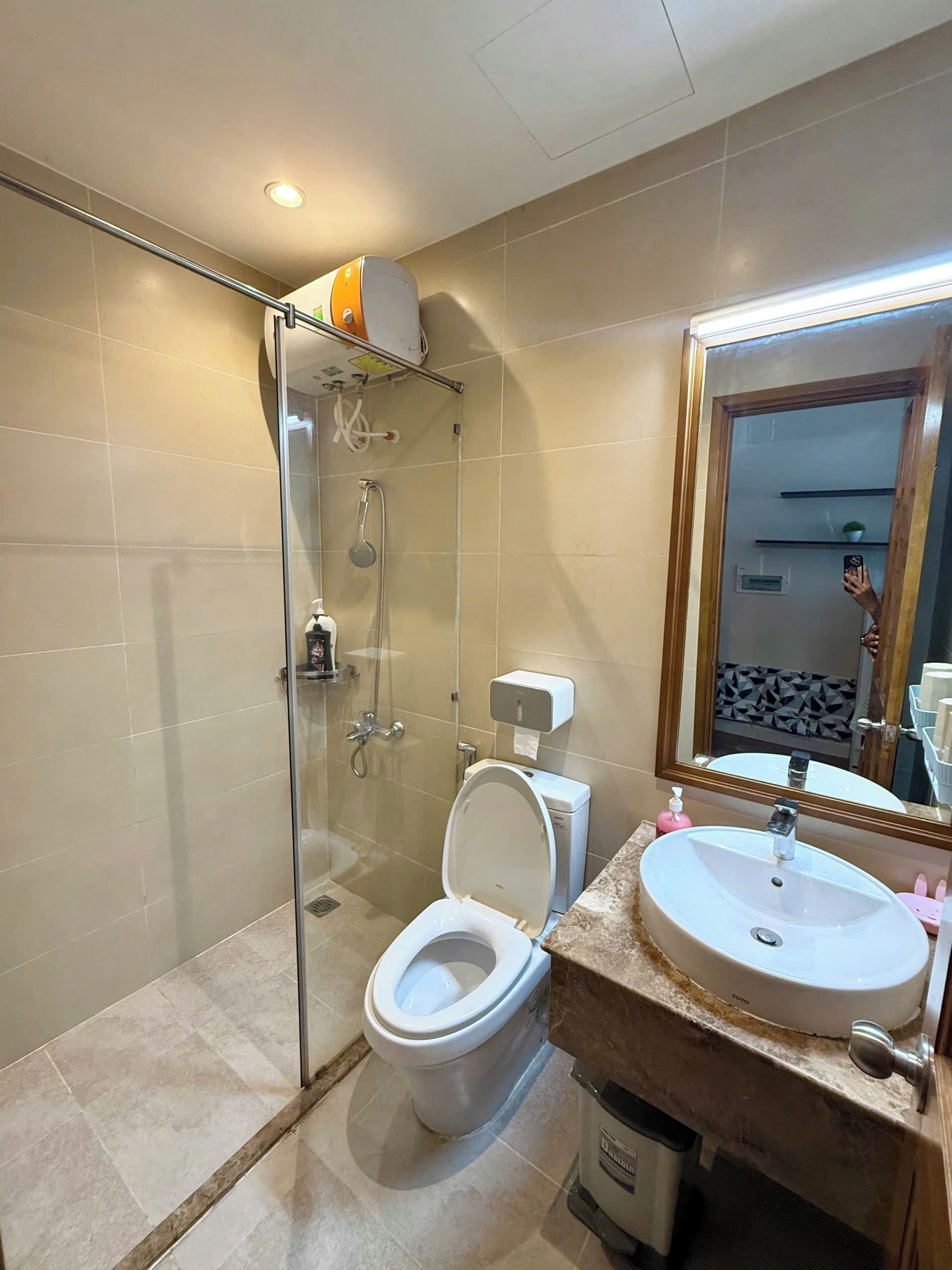 Un baño con ducha de vidrio, inodoro, lavabo y espejo.