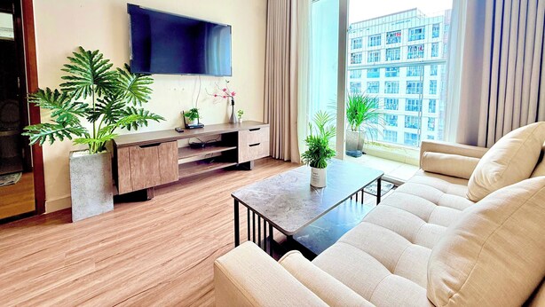 Una sala de estar moderna con televisor de pantalla plana, piso de madera, un sofá, una mesa de centro y plantas en macetas.