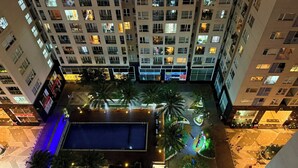 Un edificio de gran altura con varios balcones, piscina y zonas ajardinadas con palmeras.