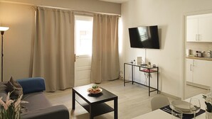 A modern living room with a sofa, a coffee table, a TV, and a kitchen area. - Santa Cruz Holiday Home (Santa Cruz de Tenerife)