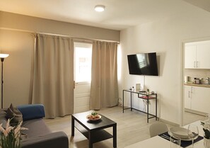 Un salon moderne comprenant un canapé, une table basse, un téléviseur et un coin cuisine.