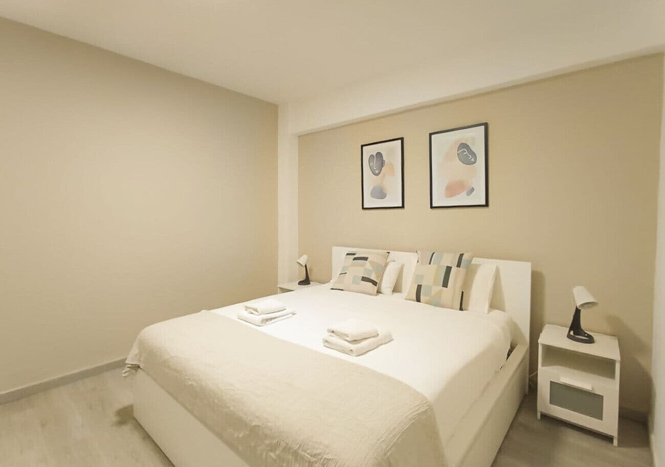 Een hotelkamer met een bed, een nachtkastje en twee ingelijste foto’s aan de muur.