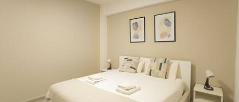 Een hotelkamer met een bed, een nachtkastje en twee ingelijste foto’s aan de muur.