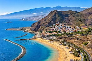 A coastal town with a beach, boats, and a mountainous backdrop. - Santa Cruz Holiday Home · 2 Bedrooms & Patio (Santa Cruz de Tenerife)