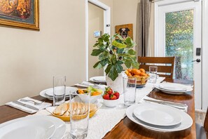 A dining table set with plates, glasses, a bowl of fruit, and a potted plant. - 4BR/4BA Tampa Retreat | Game Room & Patio (Tampa)