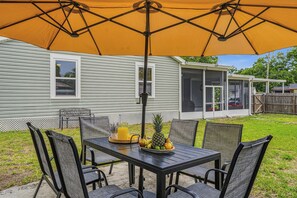 A patio with a table and chairs, an umbrella, and a fruit tray. - 4BR/4BA Tampa Retreat | Game Room & Patio (Tampa)