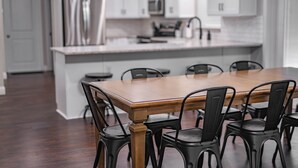 A modern kitchen with white cabinets, stainless steel appliances, and a wooden dining table with black chairs.
