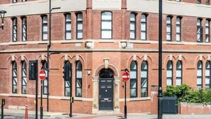Un edificio de ladrillo rojo con una cúpula central, ventanas arqueadas y una puerta negra.