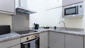 Ett modernt kök med inbyggd spis, ugn, mikrovågsugn och diskho.