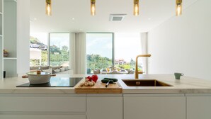 Una cocina moderna con una isla grande, vistas al exterior e iluminación colgante.