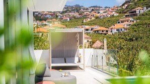 Un espacio exterior moderno con mobiliario y vistas a una zona residencial en la ladera.