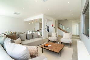A modern living room with a sofa, armchairs, and a coffee table. - Heated Infinity Pool • Cinema Room • Sea Views (Ponta do Sol)