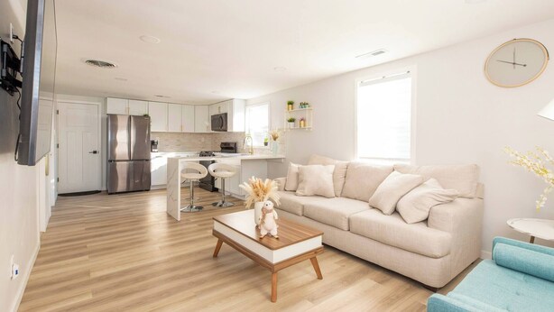 A modern living room with a sofa, a coffee table, and a dining area with a chair and a small table. - Cute Newly Remodeled Home Close to Notredame 2bed (Mishawaka)