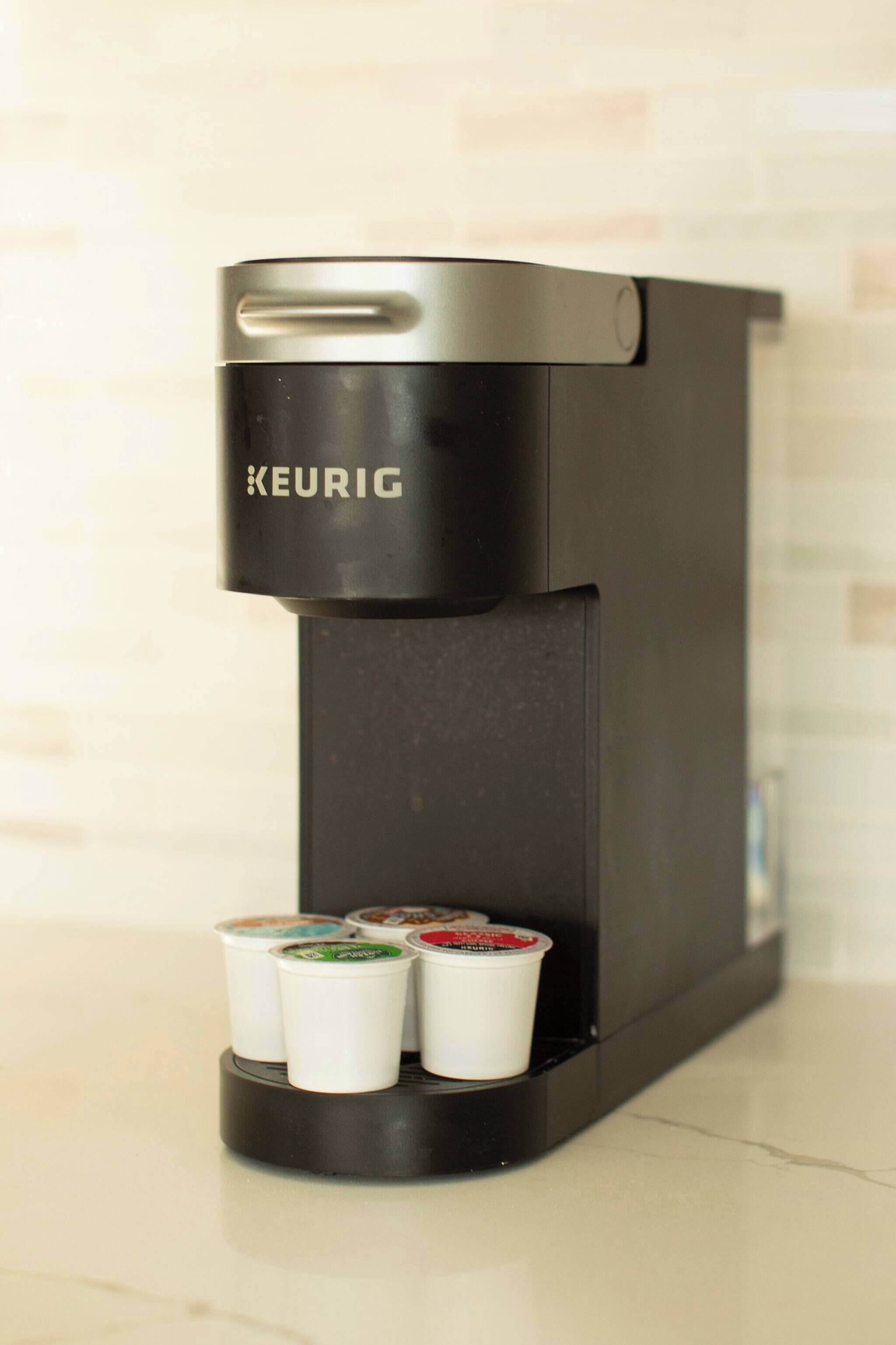 A Keurig coffee machine with three coffee pods on the drip tray.