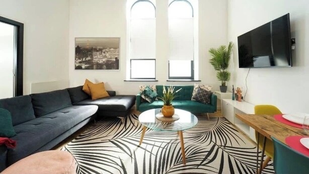Una sala de estar moderna con un sofá seccional, una mesa de centro redonda y un comedor con mesa y sillas de madera.