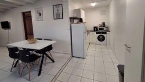 A compact kitchen with a refrigerator, microwave, and washing machine. There is a dining area with a table and chairs. - T2 neuf au Gosier - close to beaches - quiet & central, ideal for vacations (Le Gosier)