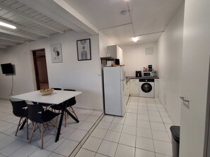 Eine kompakte Küche mit Kühlschrank, Mikrowelle und Waschmaschine. Es gibt einen Essbereich mit Tisch und Stühlen.