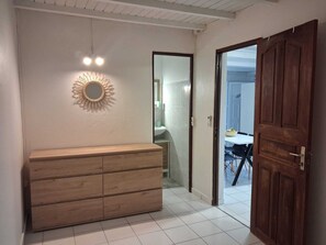 Ein Flur mit einem Holzschrank, einem Spiegel mit Sonnenstrahlendesign und einer Tür zu einem Badezimmer.