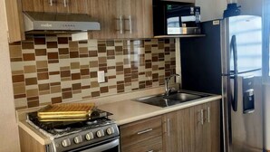 Eine moderne Küche mit Gasherd, Backofen, Edelstahlkühlschrank und Holzschränken.